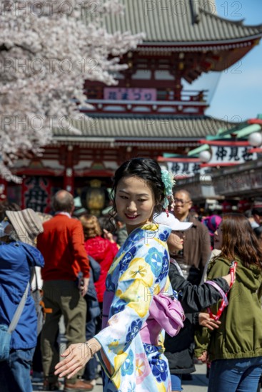 Young Japanese woman wearing kimono surrounded by numerous visitors on Nakamise-dori shopping