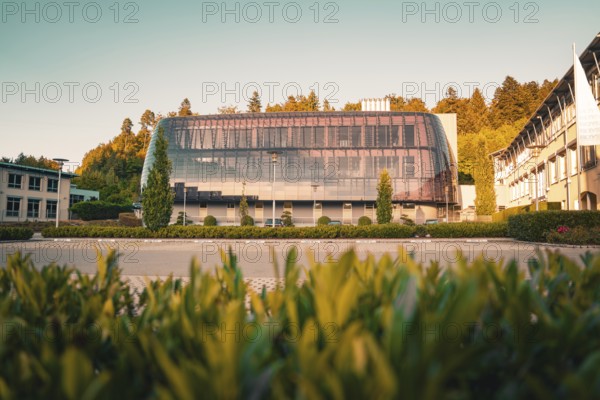 Modern building with glass façade in green surroundings, warm sunlight on the trees, Altensteig,