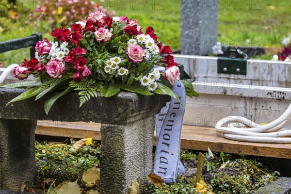 Open grave with a funeral wreath just in front of the burial of a deceased person. Pragfriedhof