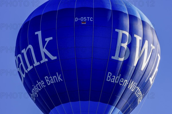 A hot air balloon, registration D-OSTC, rises into the air as part of an air show at the Rossfeld