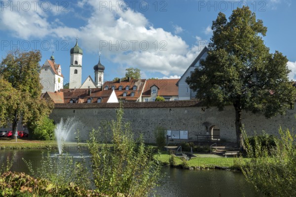Trench pond with water fountain, city wall, church towers and water tower at the back, Isny,