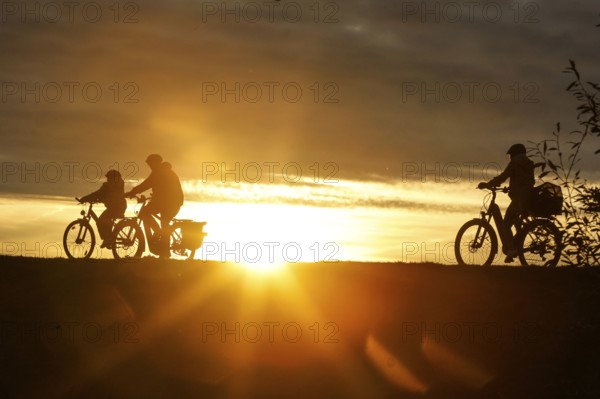 Cyclists ride on a cycle path on the island of Fehmarn at sunset, 13.10.2025, Fehmarn,