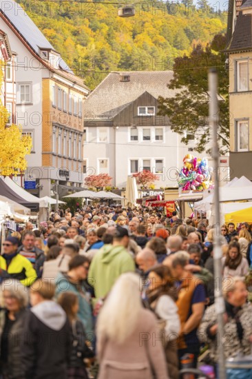 Busy shopping street in autumn, people strolling between modern buildings and colorful shops,