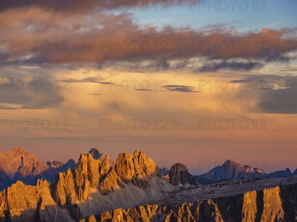 Alpine glow, rugged Dolomite peaks at sunset, colored clouds above, Dolomites, Alps, Belluno