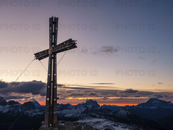 Sassongher summit cross at sunrise, in the background Monte Cristallo, Monte Pelmo and Civatta,