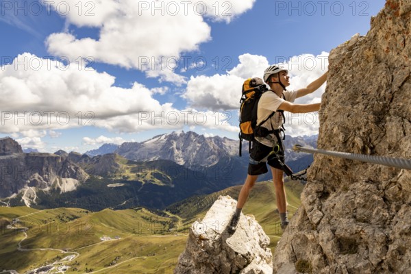 Mountaineer climbs on Ferrata Furcela de Saslonch, Langkofelscharte via ferrata, Dolomites,