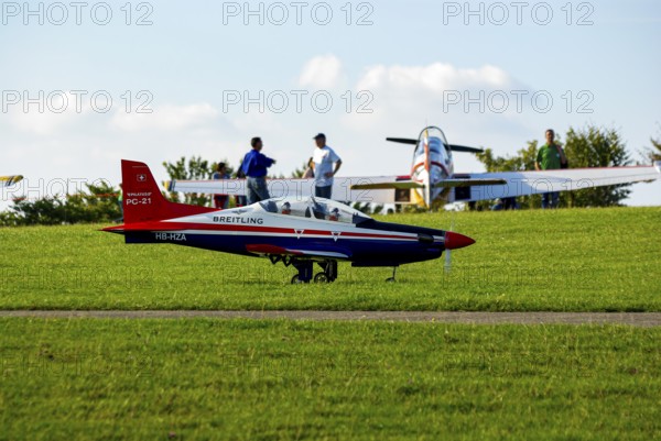An RC model of a Pilatus PC-21 with advertising for the Swiss watch brand Breitling during a flight