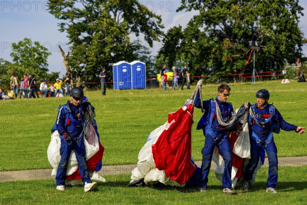 Parachutists have landed after an aerial acrobatic performance during an air show on the Rossfeld