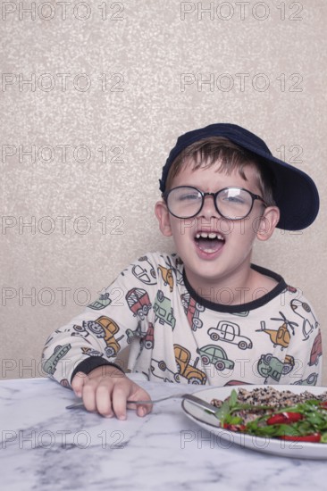 Child reacts dramatically to a salad served on a marble table at home during lunchtime, A little
