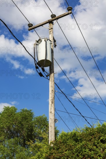 Electricity transformer, high voltage transmission wires, internet, telephone cables attached to