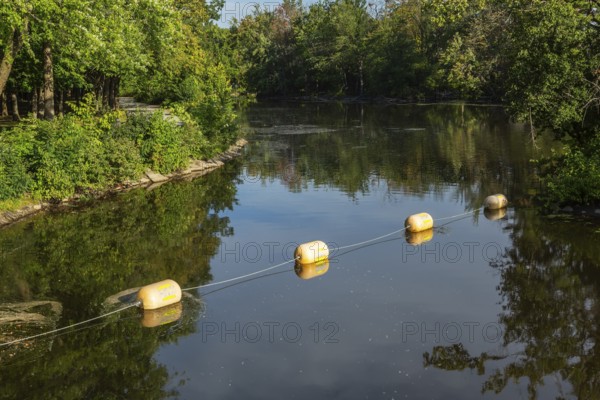 String of yellow cautionary navigation marker buoys on water surafce of river serving to warn,
