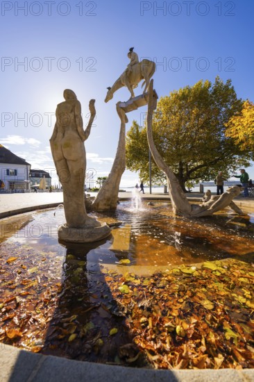 Artistic fountain with sculptures surrounded by autumn leaves and water, Überlingen, Lake