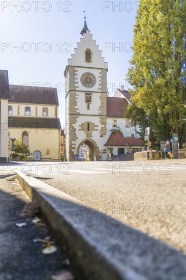 A historic tower with clock in a sunny street, surrounded by trees in autumn, Überlingen, Lake