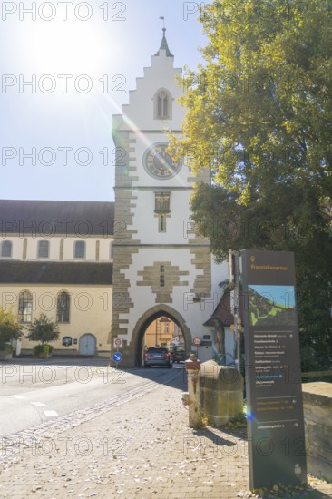 Historic town gate with church tower in the sunshine on an autumnal street, Überlingen, Lake