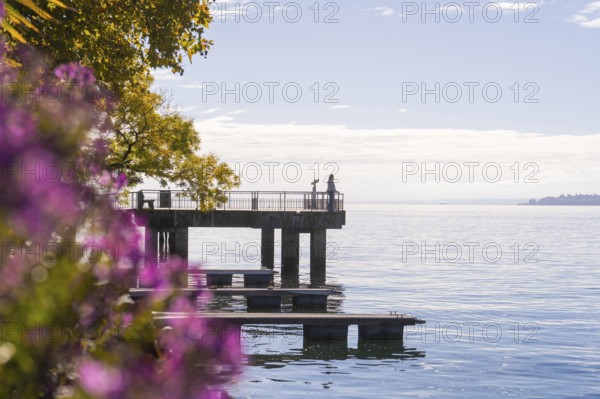 Footbridge at the water with people and autumn coloured trees in the background, Überlingen, Lake