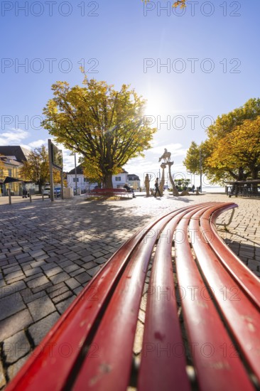 Red benches on a sunny town square surrounded by autumnal trees, Überlingen, Lake Constance,