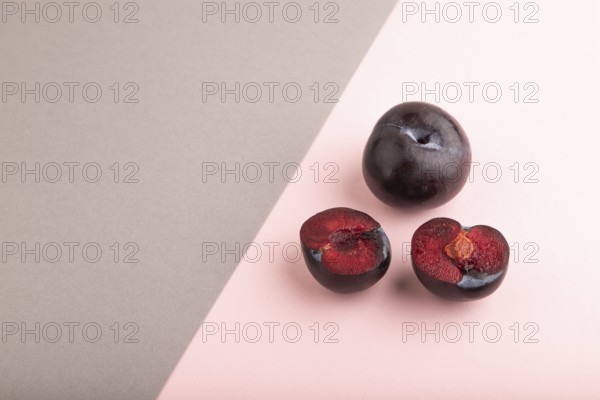 Purple Plum Cut in half on pink and gray pastel paper background. Side view, copy space. healthy