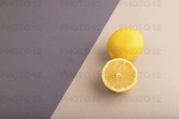 Yellow Lemon Cut in half on beige and gray pastel paper background. Side view, copy space. healthy