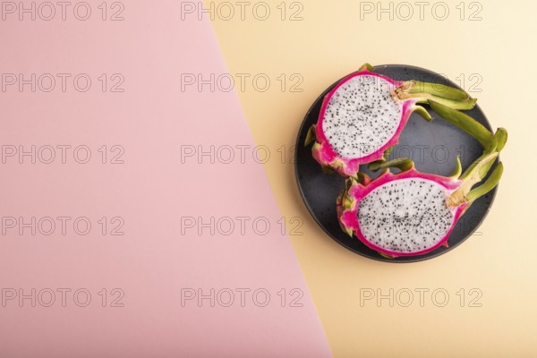 Ripe Pitaya on blue plate on pink and orange pastel paper background, top view, flat lay, copy