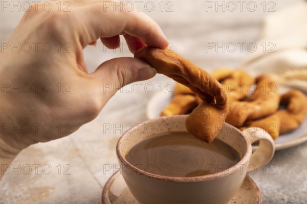 Crunchy biscuit Brushwood cookies with hand sprinkled with powdered sugar on brown concrete