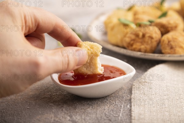 Fried crispy Chicken Nuggets with ketchup, microgreen on brown concrete background and linen