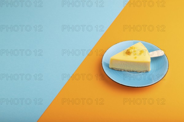 Yellow Cake pop with sprinkles on blue ceramic plate on blue and orange pastel paper background,