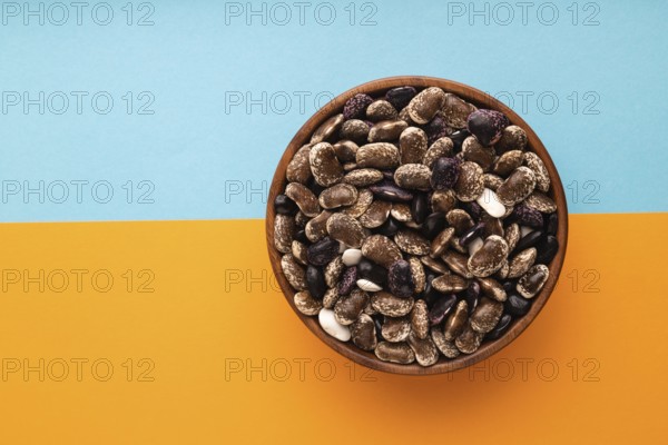 Wooden bowl with Kidney beans on blue and orange pastel paper background, top view, flat lay, copy