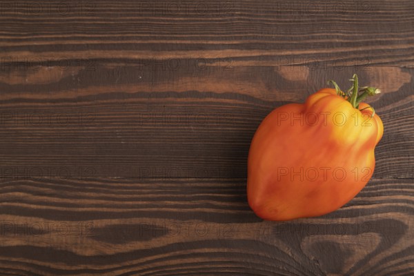 Red Heart Shape tomato on brown wooden background. Top view, flat lay, copy space. healthy food,