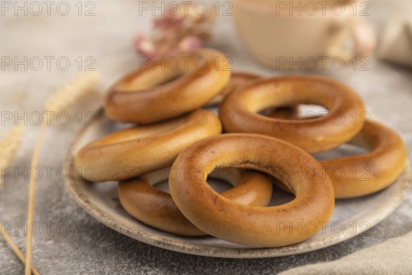 Homemade Ring Bagel with cup of coffee on brown concrete background and linen textile. side view,