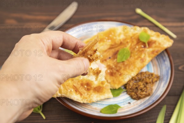 Fried homemade Khachapuri cake with cheese and meat, fried in pan with hand. Traditional Georgian