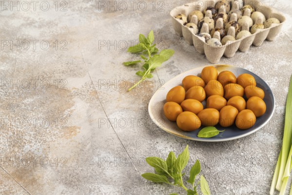 Pile of Smoked Quail eggs on plate on a brown concrete background. side view, copy space