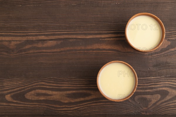 Organic non dairy banana and soy milk in clay cup on brown wooden background. Vegan healthy food