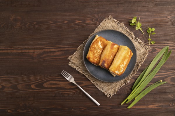Fried crispy pancakes with meat and cheese on brown wooden background and linen textile. top view,