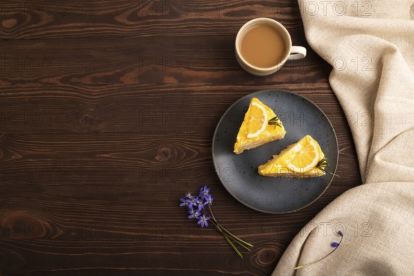 Lemon cake on brown wooden background and linen textile, cup of coffee, top view, flat lay, copy