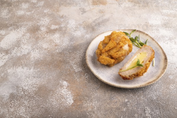 Chicken schnitzel on blue plate with microgreen on brown concrete. Diet, healthy eating. side view,