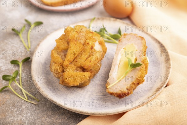 Chicken Schnitzel on blue plate with microgreen on brown concrete background and orange linen