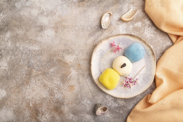 Japanese Mochi Cakes on brown concrete background and orange textile, top view, flat lay, copy