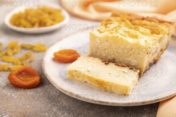 ?ottage cheese ?asserole, Curd cake, with dried apricots and raisins on brown concrete background