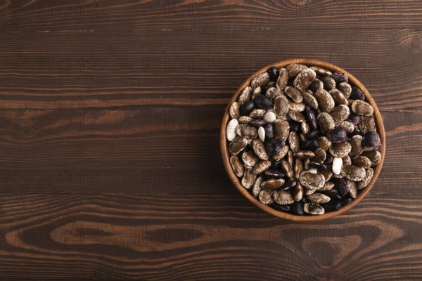 Wooden bowl with Kidney beans on brown wooden background, top view, flat lay, copy space,