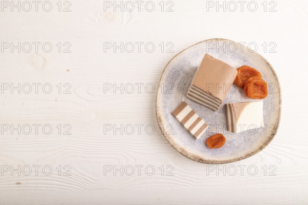 Cocoa and milk jelly with dried apricots on white wooden background, top view, flat lay, copy