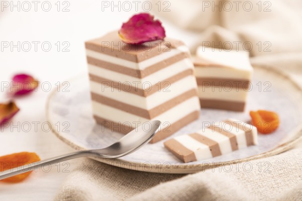 Cocoa and milk jelly with dried apricots on white wooden background and linen textile, side view,
