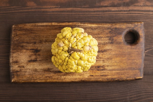 Decorative orange Pumpkin with tumors on cutting board on brown wooden background, top view, flat