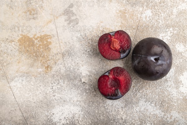 Purple Plum Cut in half on brown concrete background. Top view, flat lay, copy space. healthy food,
