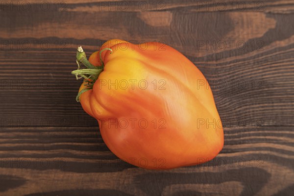 Red Heart Shape tomato on brown wooden background. Top view, flat lay, close up. healthy food,