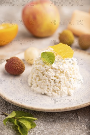 White ?ottage cheese, Curd, with orange and lychee on brown concrete background and orange textile,