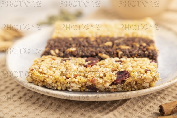 Granola bars with caramel, nuts, flakes in ceramic plate on brown concrete background, beige linen