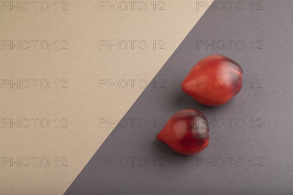 Red Heart shape tomatoes on gray and beige pastel paper background. Side view, copy space. healthy