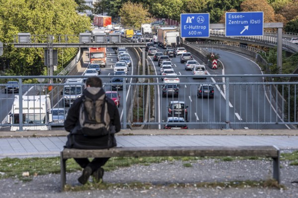 Man sitting on a bench, looking at the traffic jam on the A40 motorway, Ruhrschnellweg, in the city