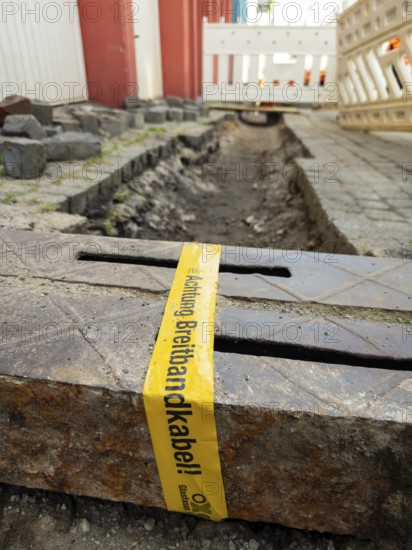 Flapping tape with the indication of an installed fibre optic cable at a construction site in