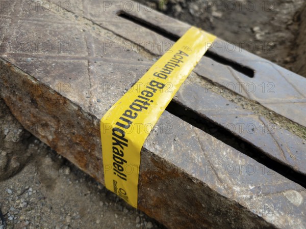 Flapping tape with the indication of an installed fibre optic cable at a construction site in